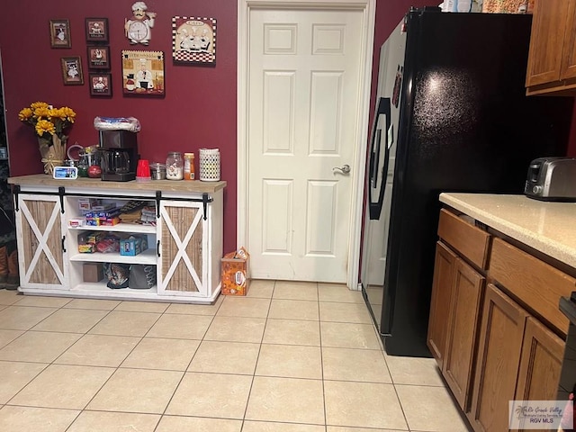 17211 Tangelo Ave, Harlingen, TX 78552 - kitchen featuring light tile patterned floors, brown cabinetry, light countertops, and black fridge