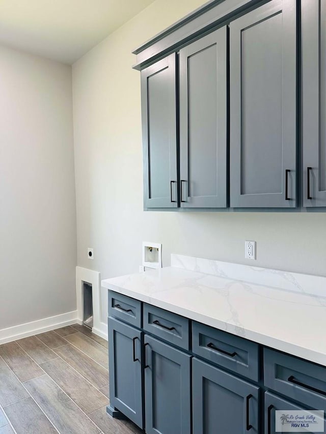 3617 Mattie Ln, Harlingen, TX 78550 - laundry area with cabinet space, electric dryer hookup, washer hookup, wood finished floors, and baseboards