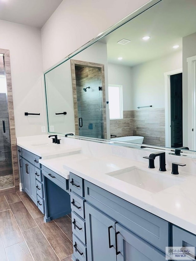 3617 Mattie Ln, Harlingen, TX 78550 - full bathroom with double vanity, a stall shower, a freestanding bath, wood finish floors, and recessed lighting