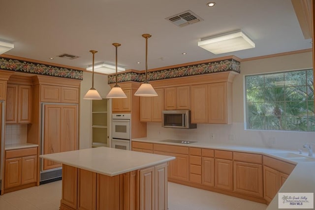 kitchen featuring black electric stovetop, decorative light fixtures, sink, ornamental molding, and a center island