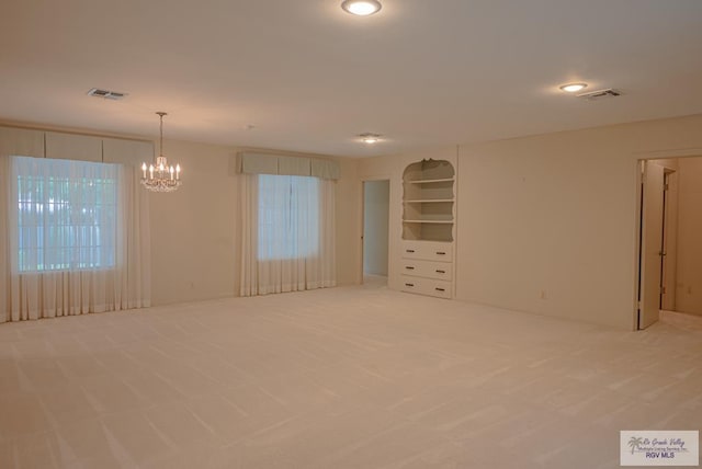 carpeted spare room featuring a chandelier and a healthy amount of sunlight