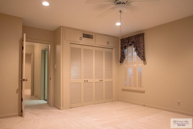 unfurnished bedroom featuring ceiling fan, light colored carpet, and a closet