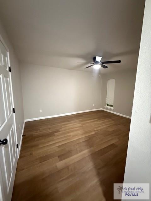 spare room with dark wood-style floors, baseboards, and a ceiling fan