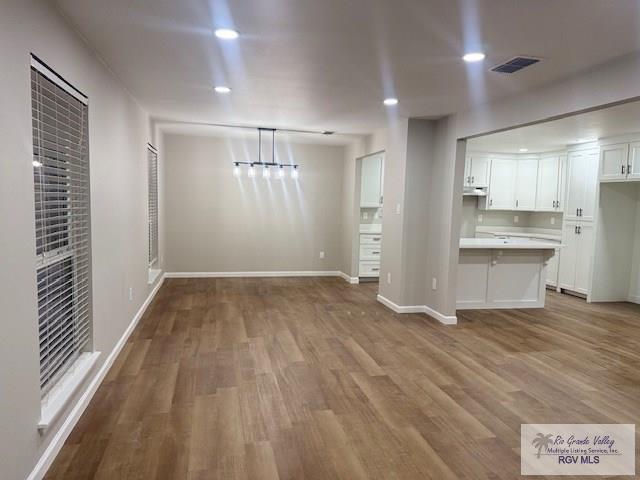 unfurnished dining area with light wood-type flooring, visible vents, baseboards, and recessed lighting