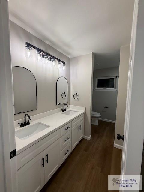 full bathroom featuring double vanity, toilet, a sink, and wood finished floors