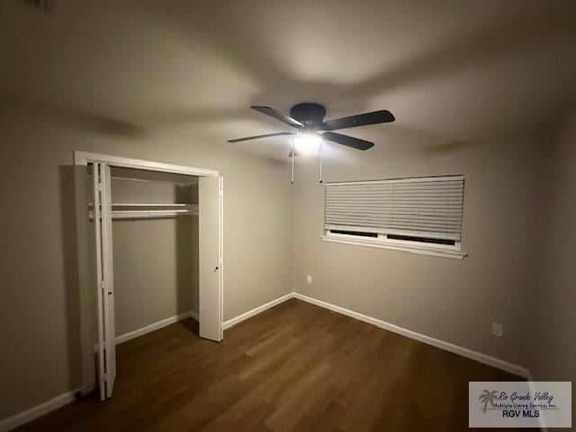 unfurnished bedroom featuring ceiling fan, a closet, baseboards, and dark wood-style flooring