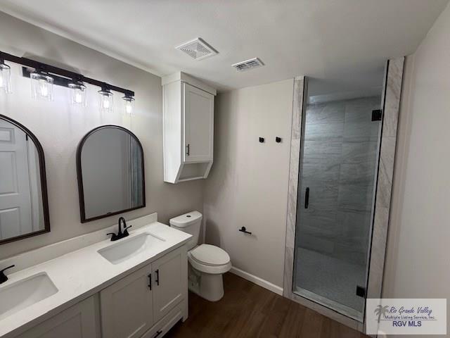 bathroom with visible vents, a sink, a shower stall, and double vanity