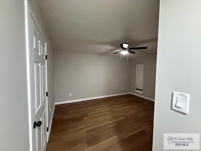 unfurnished room with baseboards, a ceiling fan, and dark wood-style flooring