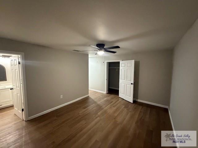 unfurnished bedroom featuring dark wood-style floors, baseboards, and a closet