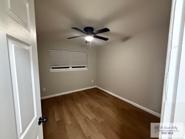 unfurnished room with dark wood-style floors, baseboards, and a ceiling fan