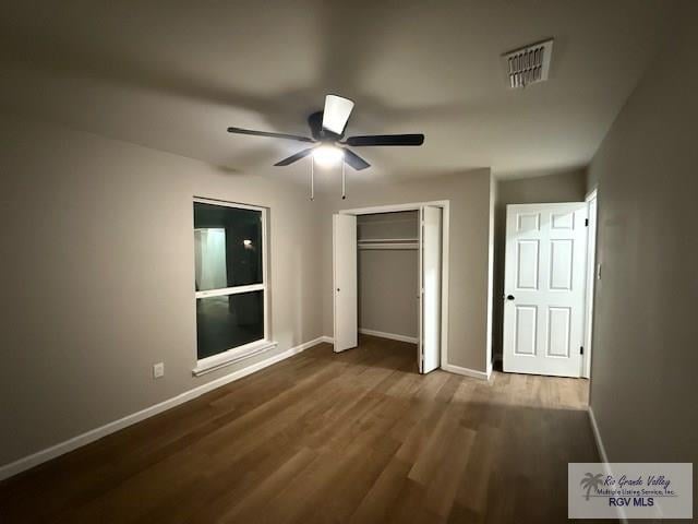 unfurnished bedroom featuring ceiling fan, dark wood-style flooring, visible vents, baseboards, and a closet