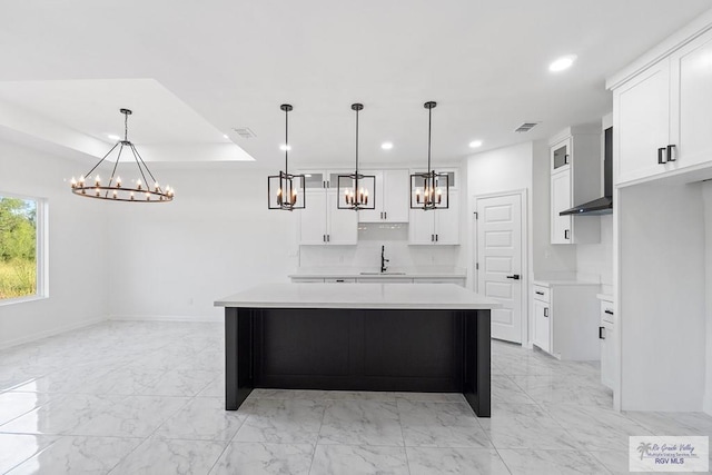 kitchen with a spacious island, sink, white cabinets, and hanging light fixtures