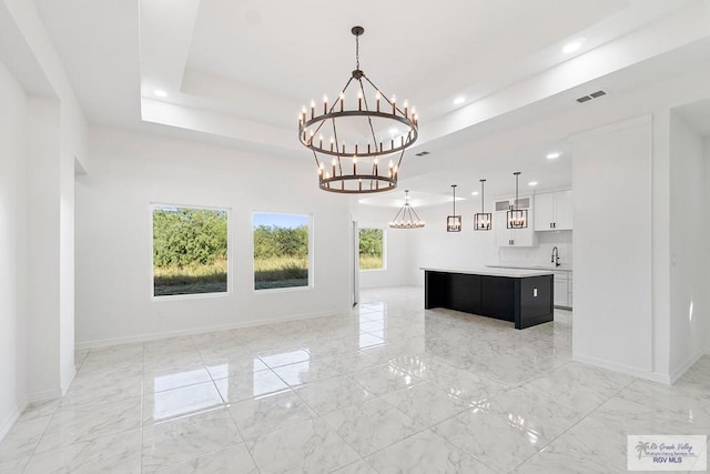 interior space with sink, a tray ceiling, and a chandelier