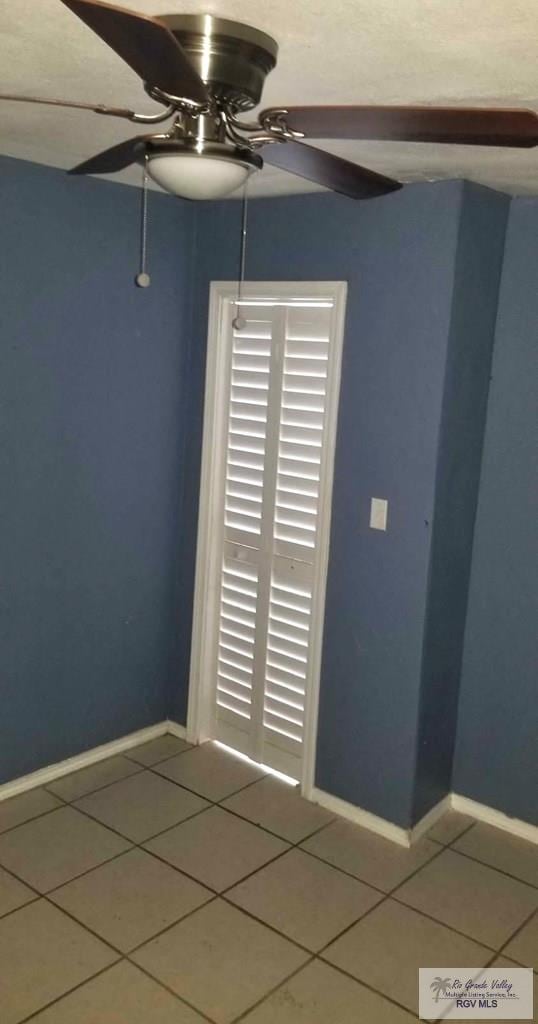 tiled spare room with ceiling fan and baseboards