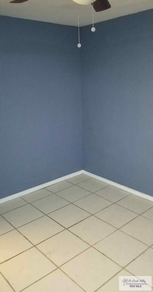 empty room featuring a ceiling fan, baseboards, and light tile patterned floors