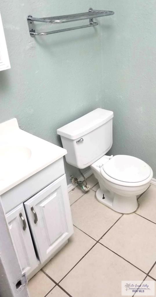 half bath featuring toilet, tile patterned flooring, and vanity