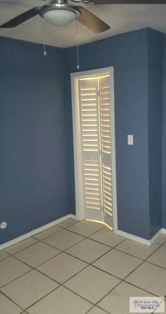 empty room featuring ceiling fan, baseboards, and tile patterned floors