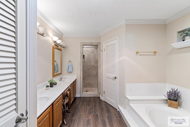 24382 Preston Trl, Harlingen, TX 78552 - bathroom featuring double vanity, a bath, a shower stall, a textured ceiling, and wood finished floors