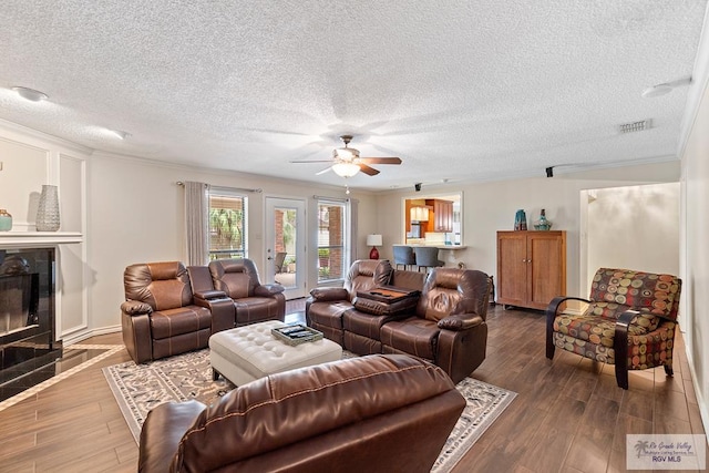 24382 Preston Trl, Harlingen, TX 78552 - living area featuring a ceiling fan, dark wood-style flooring, a textured ceiling, ornamental molding, and a tile fireplace