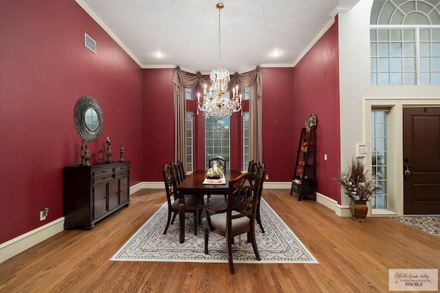 dining area featuring a chandelier, light hardwood / wood-style flooring, and crown molding