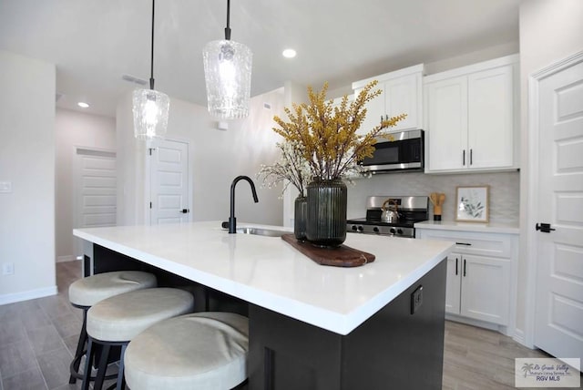 1838 Miley Ln, Harlingen, TX 78550 - kitchen with stainless steel appliances, a kitchen island with sink, white cabinetry, recessed lighting, and decorative light fixtures