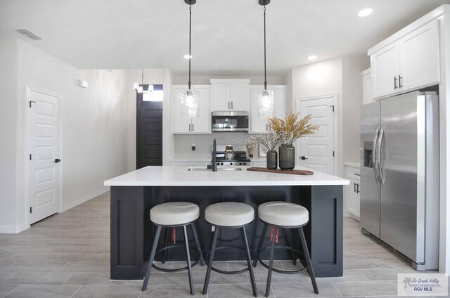 1838 Miley Ln, Harlingen, TX 78550 - kitchen with stainless steel appliances, white cabinets, light countertops, a kitchen island with sink, and recessed lighting