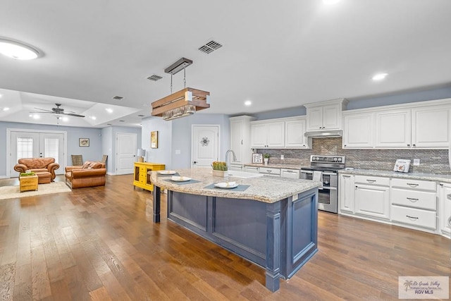 kitchen featuring stainless steel range with electric cooktop, white cabinets, dark hardwood / wood-style floors, ceiling fan, and light stone countertops