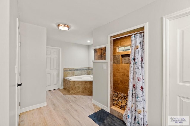 bathroom featuring plus walk in shower and wood-type flooring