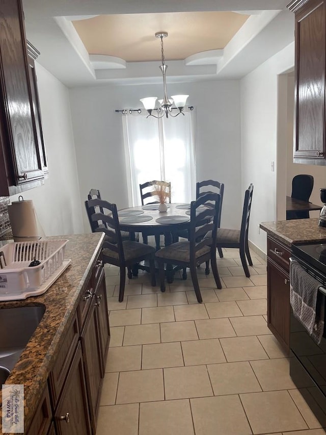 tiled dining space with a raised ceiling and a notable chandelier