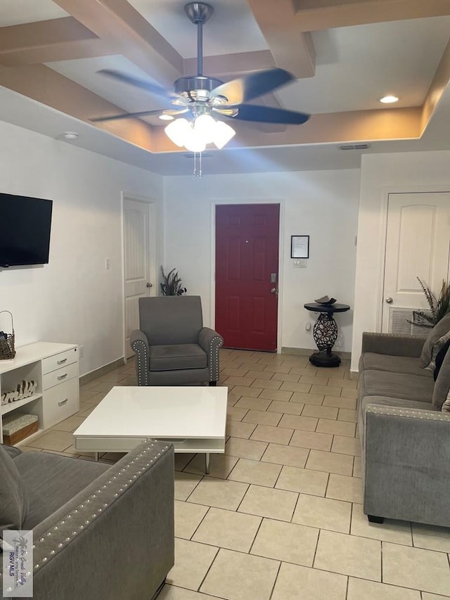 tiled living room with coffered ceiling, a raised ceiling, and ceiling fan