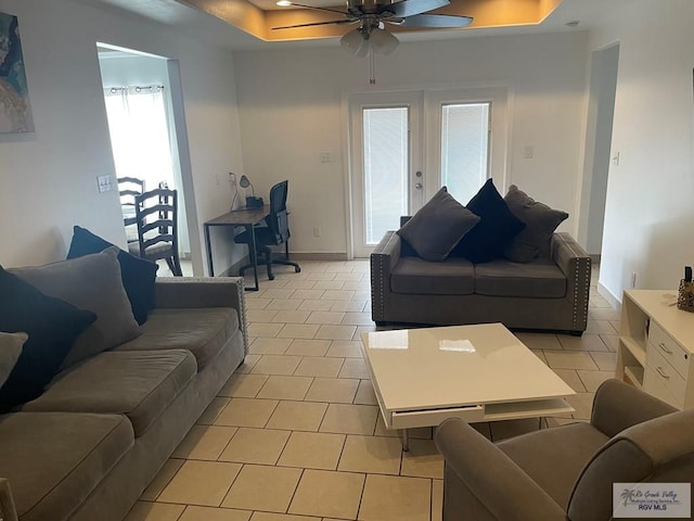 living room with light tile patterned flooring, ceiling fan, a raised ceiling, and french doors