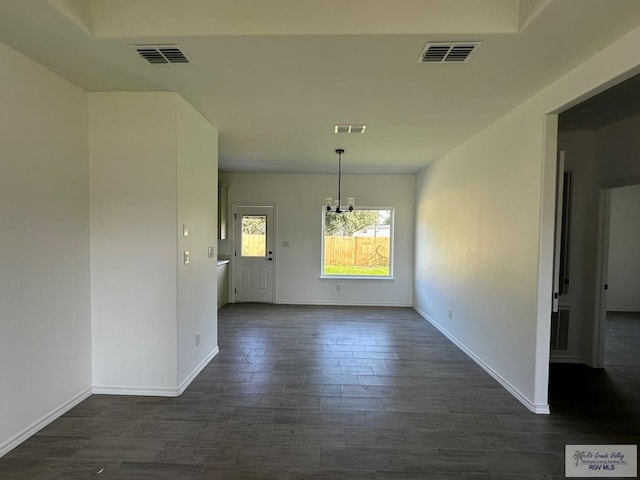 unfurnished dining area with dark hardwood / wood-style floors and an inviting chandelier