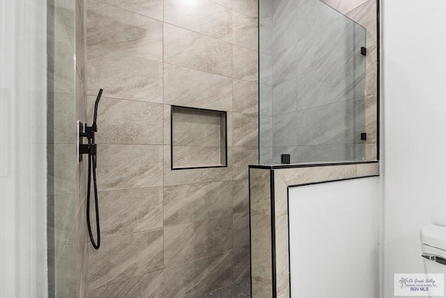 bathroom with a tile shower and toilet