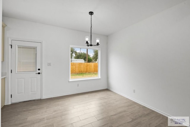 unfurnished dining area with a notable chandelier and light hardwood / wood-style floors