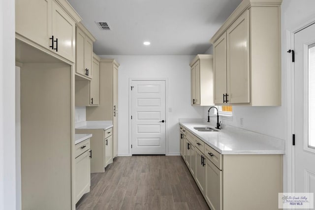 kitchen with light hardwood / wood-style floors, sink, and cream cabinetry