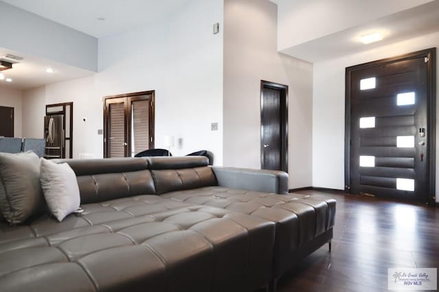 interior space featuring stainless steel refrigerator with ice dispenser, dark hardwood / wood-style flooring, and a high ceiling