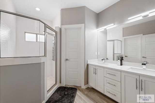 bathroom with wood-type flooring, vanity, and an enclosed shower