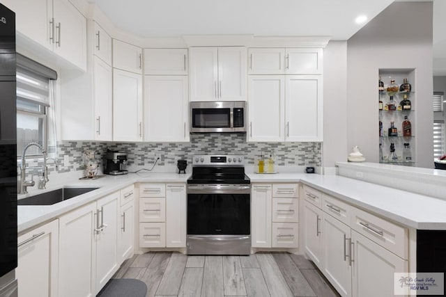 kitchen featuring stainless steel appliances, white cabinetry, tasteful backsplash, and sink