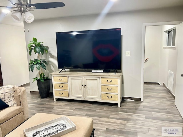 living room with a ceiling fan, light wood-type flooring, visible vents, and baseboards