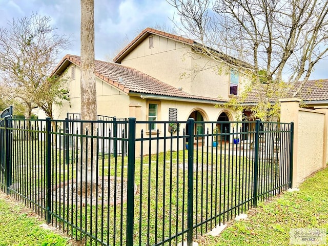 view of gate with a lawn and a fenced backyard