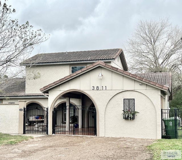 view of front of house with a gate, fence, a tiled roof, and stucco siding