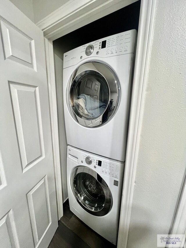 laundry room with laundry area, dark wood finished floors, and stacked washer and clothes dryer