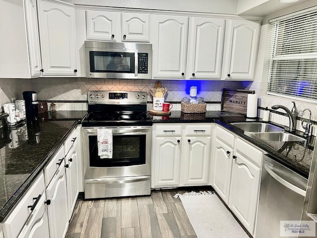 kitchen featuring stainless steel appliances, white cabinetry, a sink, and light wood-style flooring