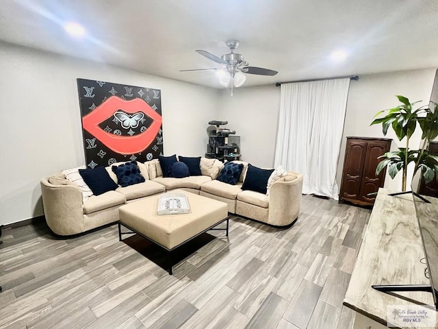 living room featuring light wood-type flooring, ceiling fan, and baseboards