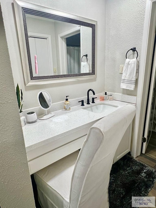 bathroom with a textured wall and vanity