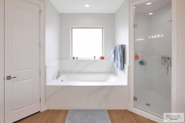 bathroom featuring wood-type flooring and shower with separate bathtub