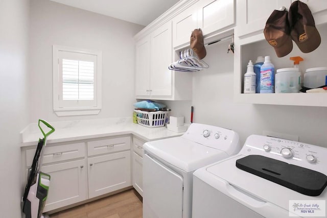 laundry area with washer and dryer, cabinets, and light hardwood / wood-style flooring