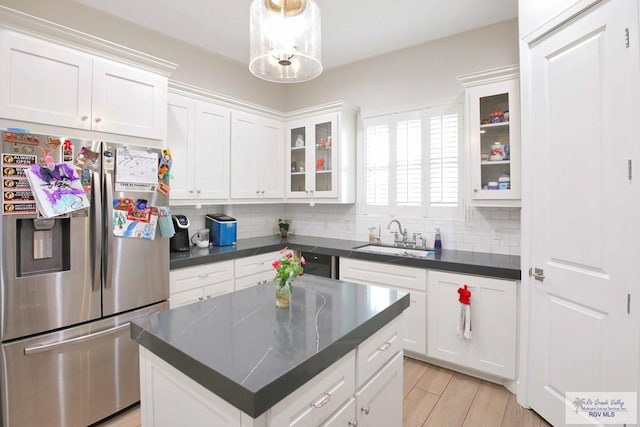 kitchen featuring sink, a kitchen island, stainless steel refrigerator with ice dispenser, backsplash, and white cabinets