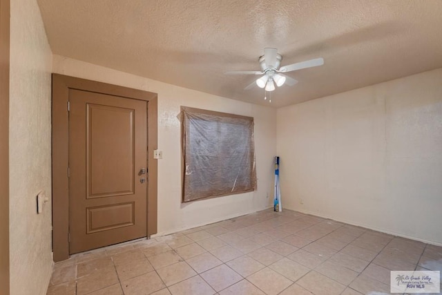 spare room featuring light tile patterned floors, ceiling fan, and a textured ceiling