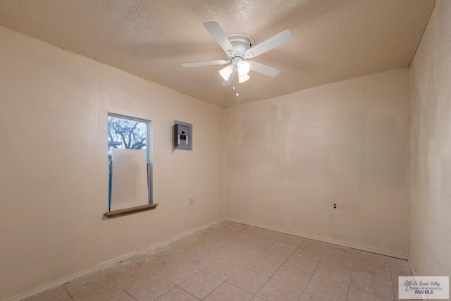 spare room featuring a ceiling fan, electric panel, a textured ceiling, and light tile patterned flooring